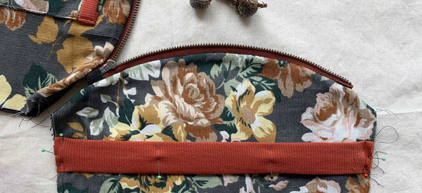 a close up image of the interior of a pouch featuring floral fabric and a rust coloured knit band
