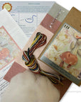 Embroidery kit with patterned paper, thread, and packaging on a white background