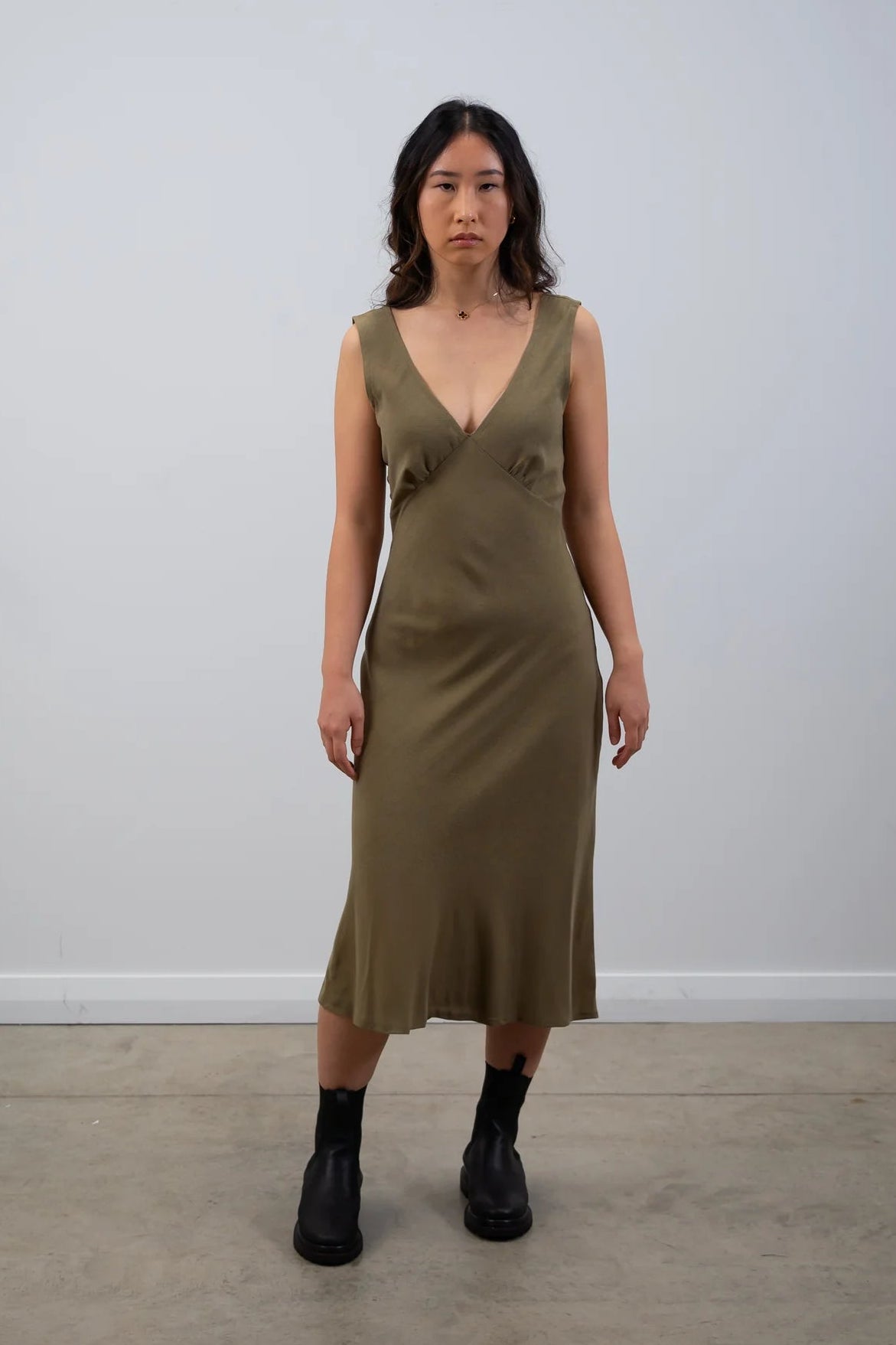 Woman wearing a green dress standing against a plain white background