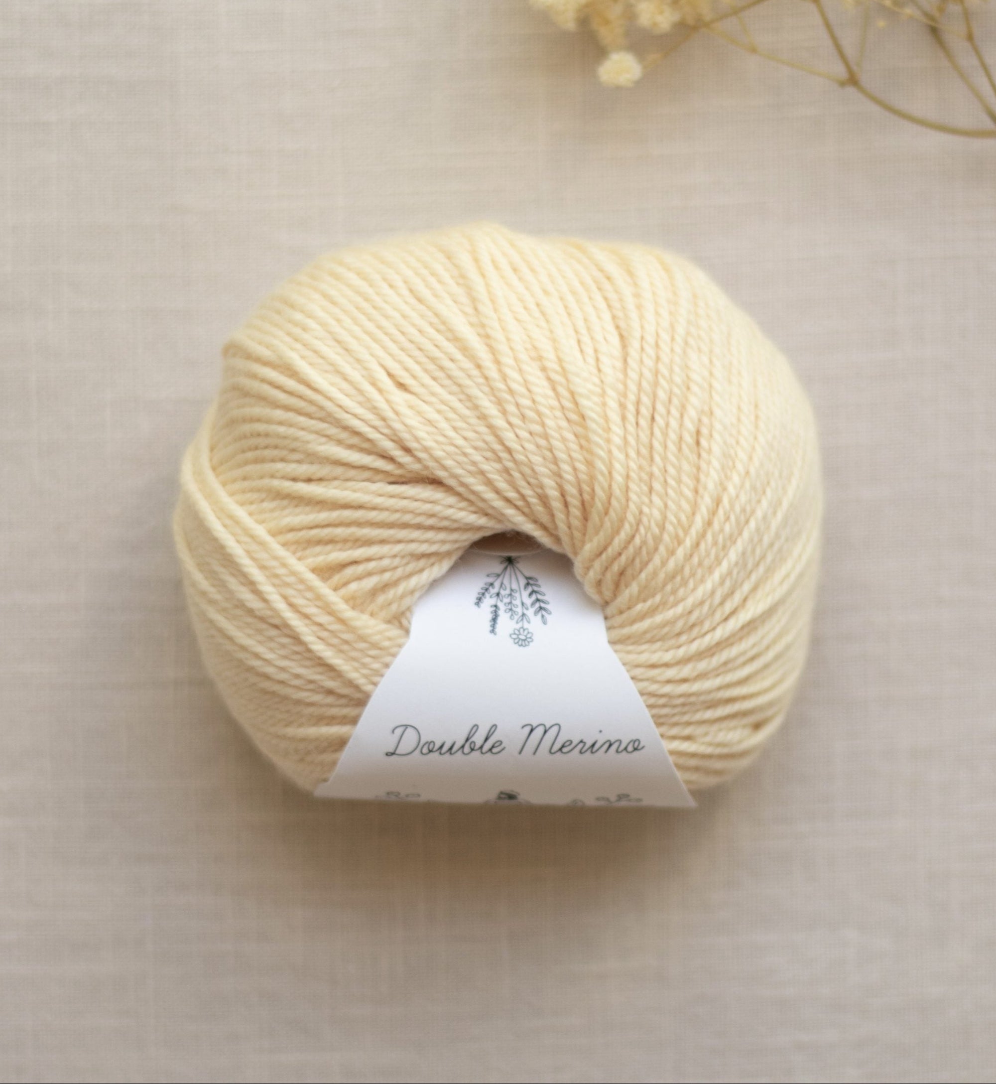 Ball of cream-colored yarn with a label on a beige background