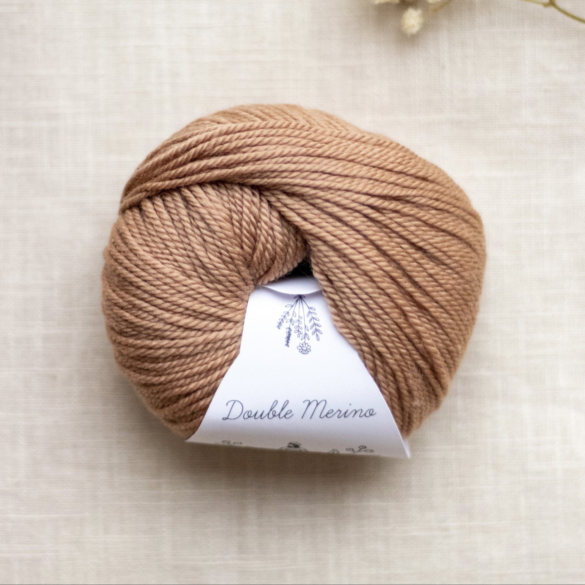 Ball of brown yarn with a label on a light beige background