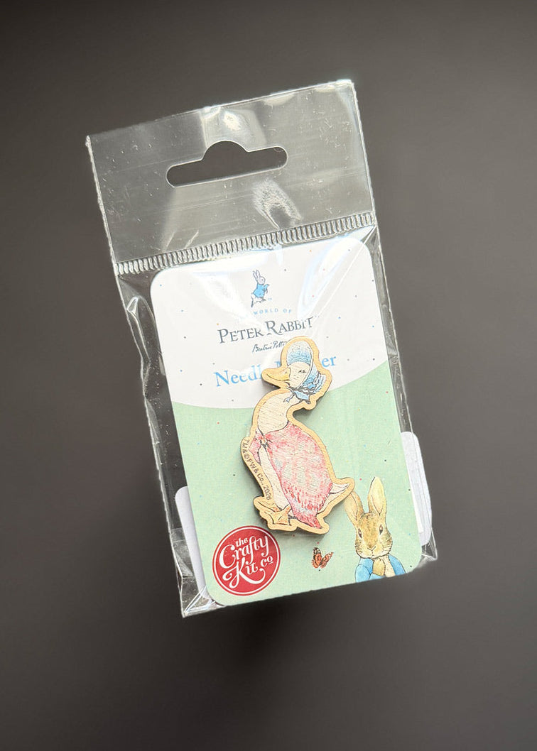 A Beatrix Potter 'Petty Rabbit' enamel pin in its original clear plastic packaging with a white backing card, displayed on a dark gray background.