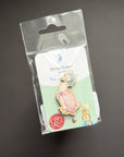 A Beatrix Potter 'Petty Rabbit' enamel pin in its original clear plastic packaging with a white backing card, displayed on a dark gray background.