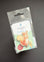 A Peter Rabbit Needle Mint pin in its original clear plastic packaging, featuring an illustration of a squirrel and a rabbit, set against a dark gray background.